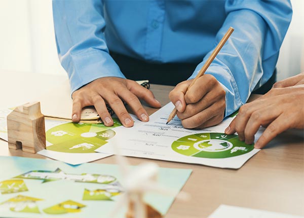 Fotografía de personas trabajando sobre una mesa con folios con motivos de medioambiente impresos en ellos