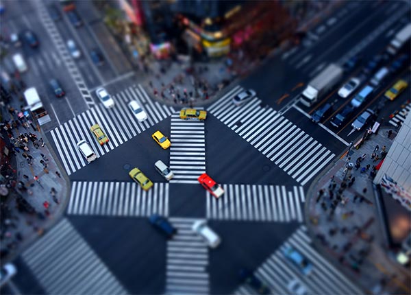 Fotografía aérea de un cruce de calles en una ciudad con pases de peatones en los lados y en cruz